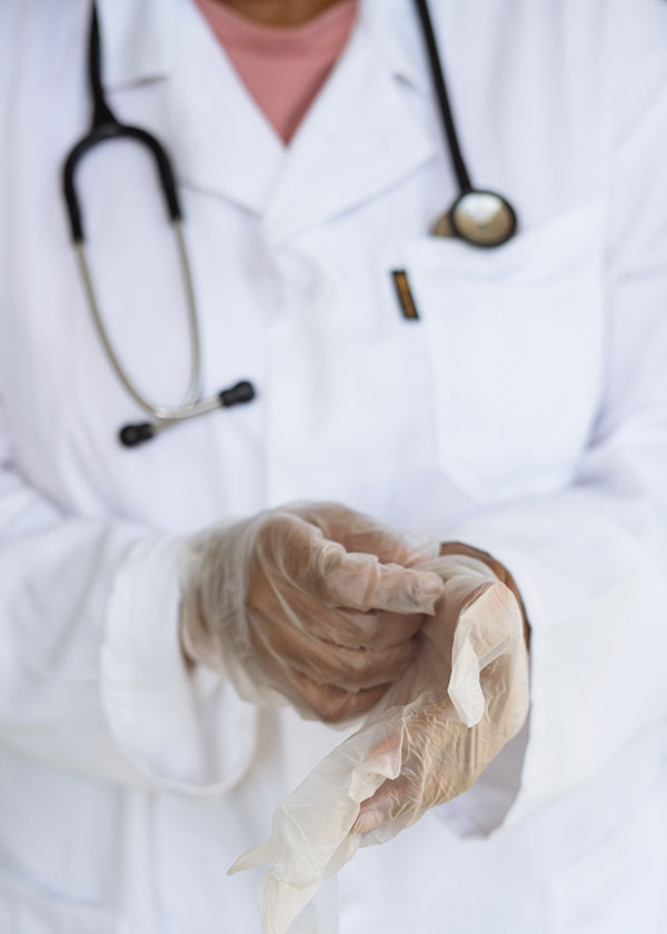 Person in white lab coat taking off rubber gloves