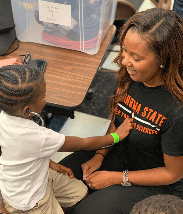 Mother's son uses a stethoscope on her.