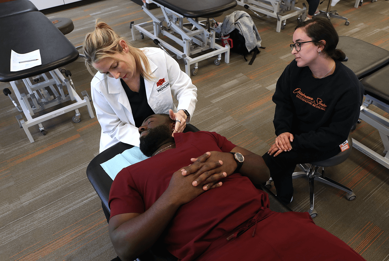 Doctor using osteopathic manipulation techniques on student.