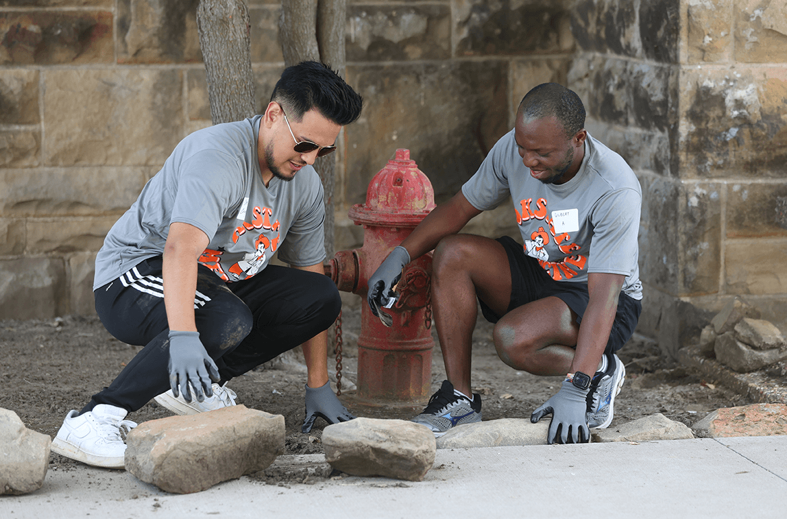 Medical students Chris Coronado (left) and Gilbert Ateh refresh a flowerbed outside Sperry, Okla., town hall.