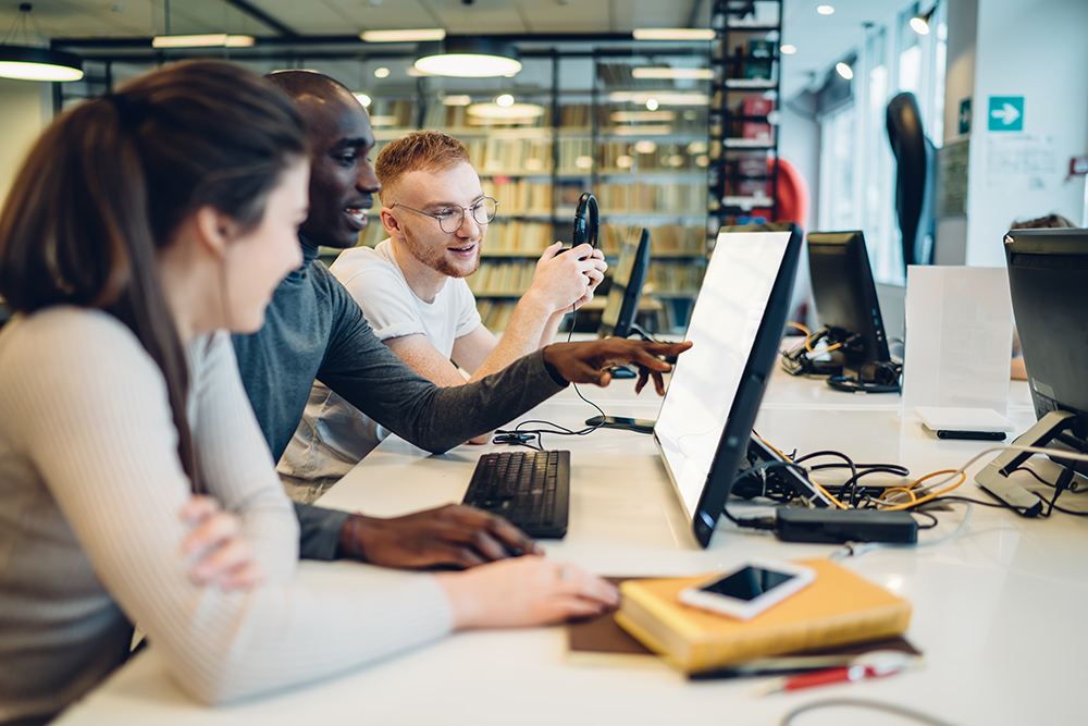 Interested multiracial students using computer while studying in library