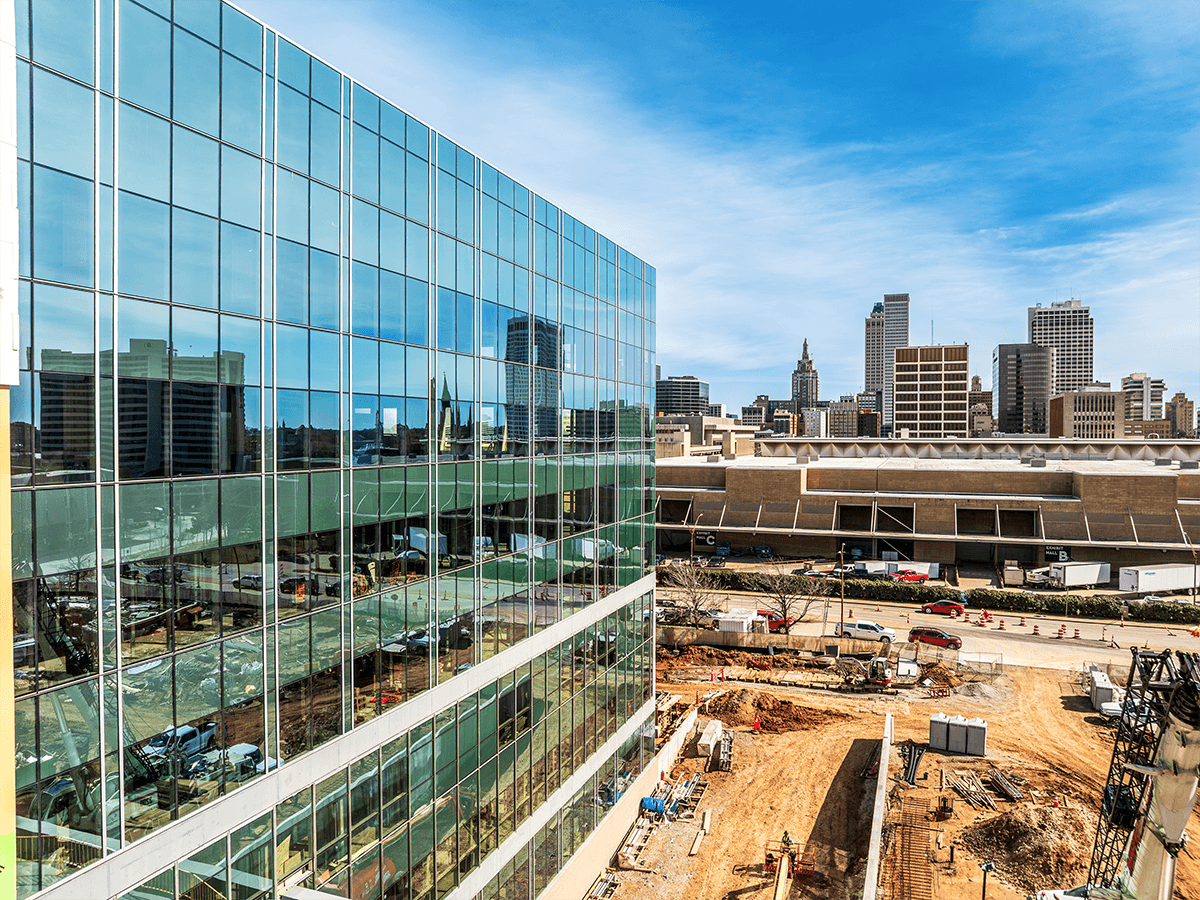 The reflection of the Tulsa cityscape visible through the glass panels of the Veterans Hospital construction.